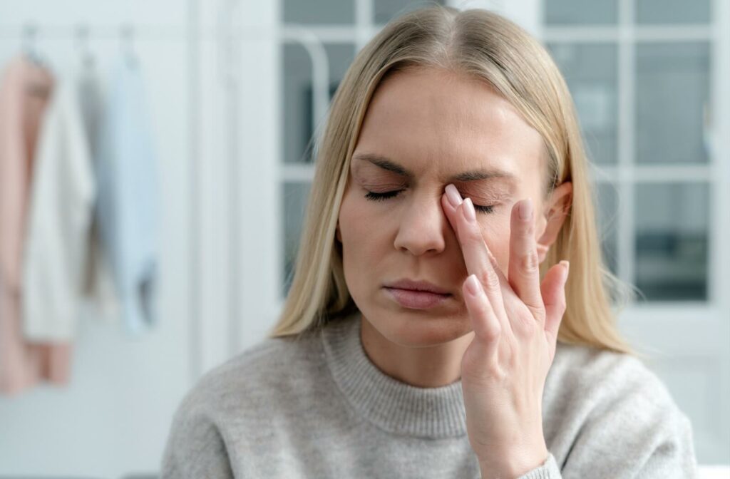 An adult rubs their irritated eye and wonders if they dryness is related to their contact lens wear.