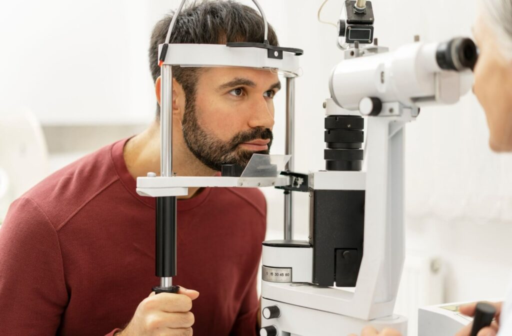 An optometrist uses a slit-lamp to examine their patient's eye during an eye exam.