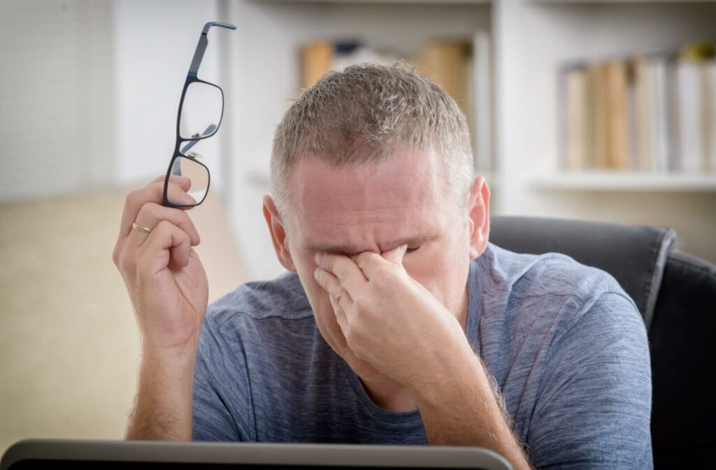 A person on a computer who is rubbing their eyes due to dry eye symptoms caused by excessive screen time.